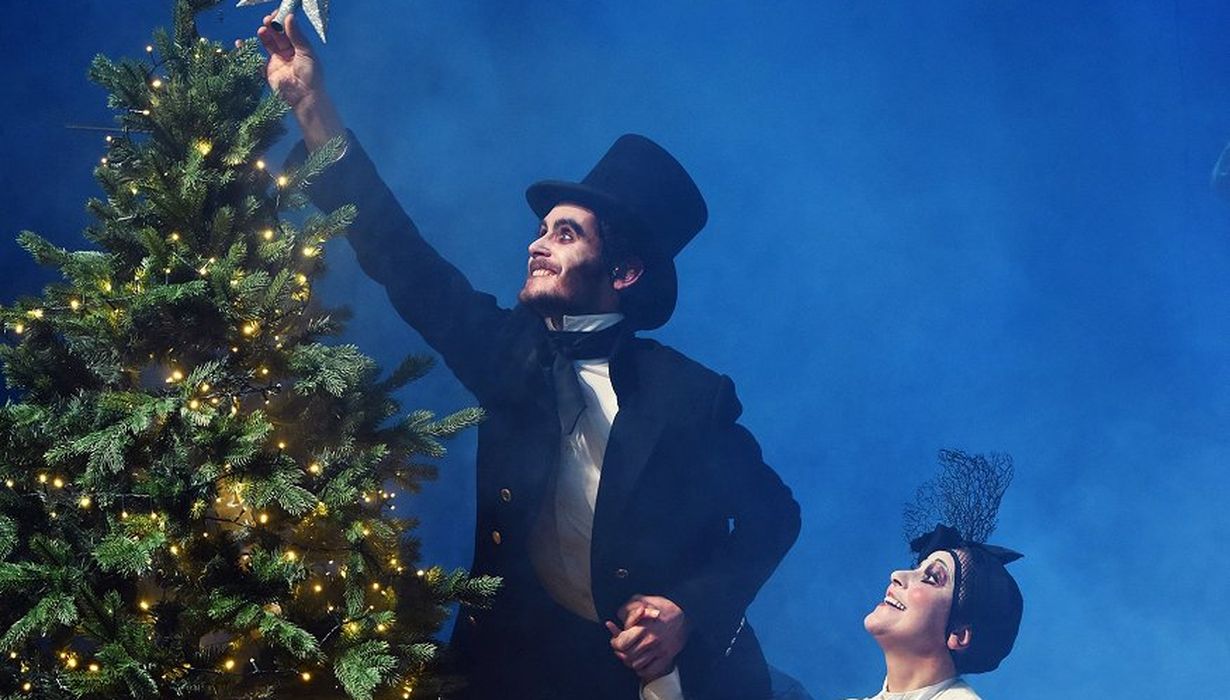 Two actors in a play (one man and a woman) placing a Christmas star on a Christmas tree.  ©SNG Nova Gorica